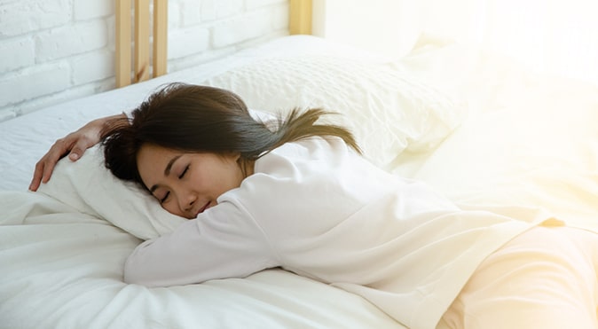 Woman sleeping on stomach in bed, Better Sleep Council