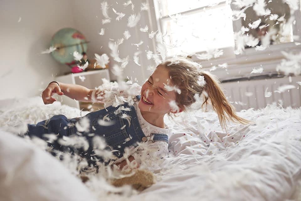 Girl falling on feather pillow fight bed