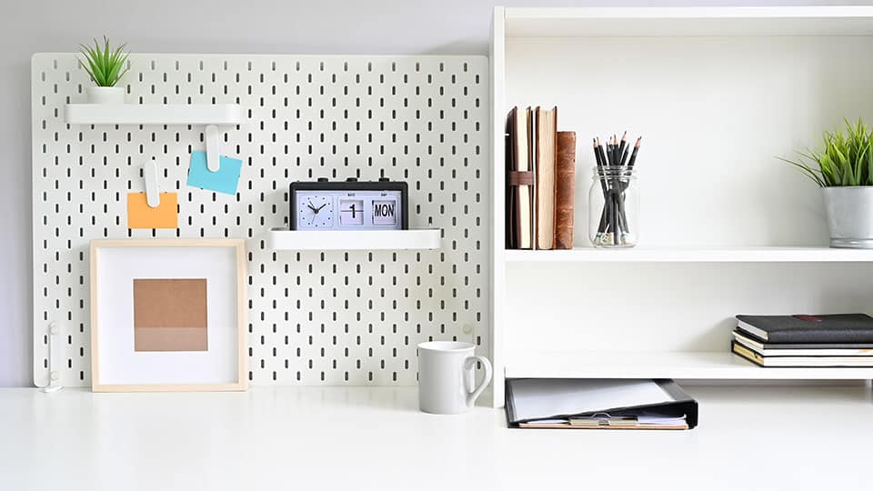 Shelves and pegboard with office supply on workspace table.