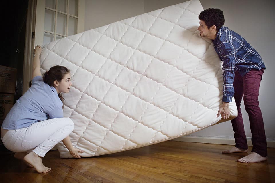 Couple Carrying Mattress In Room